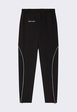 Pantalones deportivos negros con cinturilla elástica, que presentan acentos blancos a lo largo de los lados y un bolsillo trasero. La marca está impresa en la cintura.
