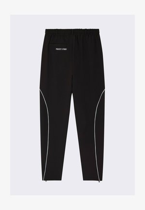 Pantalones deportivos negros con cinturilla elástica, que presentan acentos blancos a lo largo de los lados y un bolsillo trasero. La marca está impresa en la cintura.