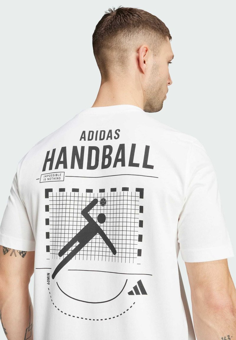 Camiseta blanca de algodón con un gran gráfico negro de un jugador de balonmano en la parte posterior, con el texto "ADIDAS HANDBALL" encima.