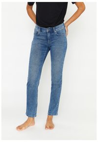 Jeans in denim blu con un design aderente, vita media, stile a cinque tasche e una leggera scoloritura sulle cosce e sulle ginocchia.