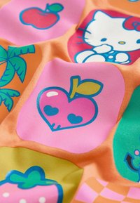 Tissu coloré avec des icônes de dessins animés comprenant une pomme rose en forme de cœur, un palmier, une fraise et un chat blanc avec un nœud rouge.