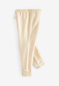Pantalons de jogging beiges avec taille élastique, cordon de serrage, tissu texturé, fermeture éclair sur le côté et petit nœud au bas.