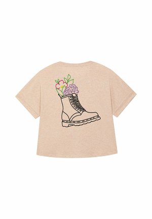 T-shirt beige con un contorno nero di un boots riempito di fiori colorati, posizionato sul retro. Design casual e artistico.
