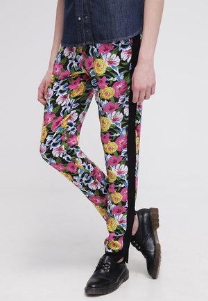 Pantalons fleuris avec un motif éclatant de roses et de lys en rose, jaune et bleu sur un fond noir, avec des bandes latérales noires.