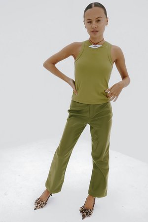 Canottiera aderente verde oliva e pantaloni a zampa abbinati, realizzati in tessuto liscio. Accentuati con tacchi leopardati e una collana decorativa.