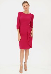 Fuksjowa sukienka o dopasowanym kroju, z rękawami 3/4 z bufkami i drapowanym akcentem falbany z boku. Noszona z srebrnymi szpilkami na kostkę.