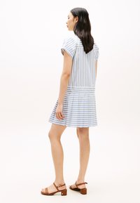 Μπλε και λευκό ριγέ φόρεμα με κοντά μανίκια και πλισέ φούστα, κατασκευασμένο από ελαφρύ ύφασμα, συνδυασμένο με καφέ σανδάλια με τακούνι.