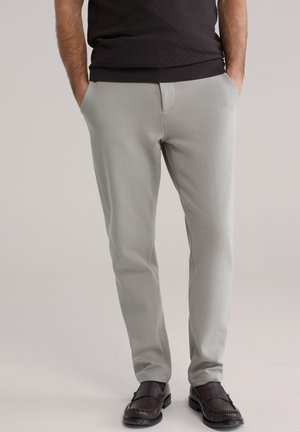 Lichtgrijze broek in een slim fit, gemaakt van zachte stof met een gladde textuur, voorzien van voorzakken en gedragen met donkerbruine loafers.