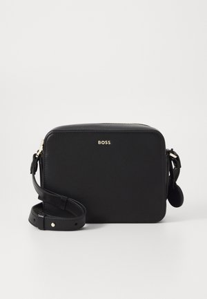 Čierna kožená crossbody taška s obdĺžnikovým tvarom, zlatým logom, nastaviteľným popruhom a zipsovým uzáverom. Hladká textura, minimalistický dizajn.