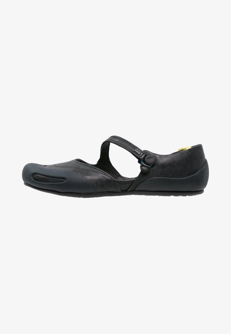 Chaussure plate Mary Jane noire minimaliste avec une bride unique, un bout arrondi et une semelle fine, vue de côté sur fond blanc.