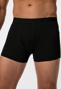Boxer shorts noirs en tissu doux, dotés d'une taille élastique stretch avec un logo texturé et d'une coupe ajustée.