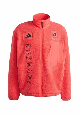Chaqueta de forro polar en coral brillante con cuello alto, cremallera frontal y texto negro "GERMANY". Incluye parches de logotipo en el pecho y el bolsillo lateral.