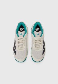 White athletic shoes with mesh upper, black accent stripes, turquoise lining, and textured sole. Features laces and branded logo.