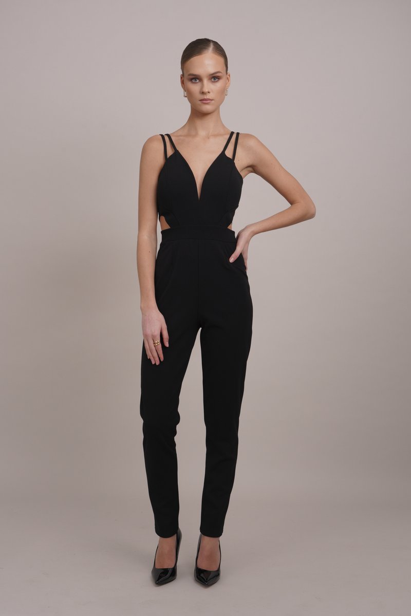 Črno kombinezo z globokim izrezom, tankimi naramnicami, stranskimi izrezki in oprijetimi hlačnicami, dopolnjujejo sijoče črne salonarji s tankim peto.