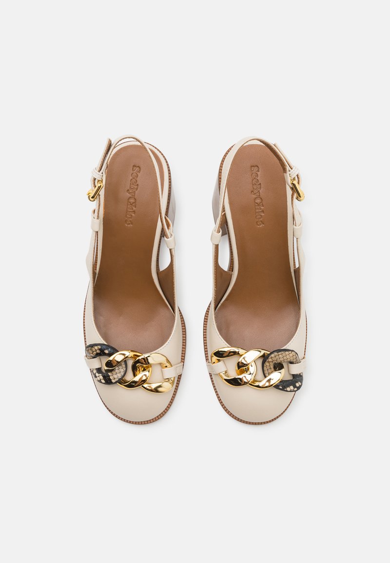 Beige Slingback-Absatzschuhe mit einer glatten Lederoberfläche, die eine dekorative goldene Kette und ein strukturiertes schwarzes Akzent besitzt. Flaches Absatzdesign.