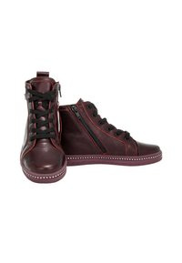 Baskets montantes en cuir rouge foncé avec des lacets noirs, fermeture éclair sur le côté, et des clous sur la semelle, présentées avec une chaussure vue de face et l'autre de côté.