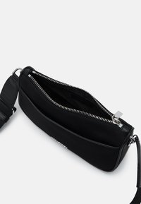 Czarna torba na ramię o gładkim wykończeniu, z zamknięciem na zamek błyskawiczny i srebrnymi akcentami. Posiada regulowany pasek oraz przestronną komorę wewnętrzną.