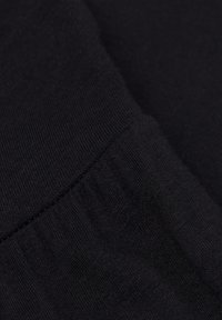 Svart tyg med en mjuk, stickad struktur. Närbild som framhäver den släta, fina väven och den subtila sträckningen i materialet.