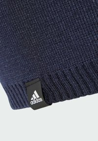 Navy knitted beanie with ribbed texture, featuring a black tag with the white Adidas logo on the side.