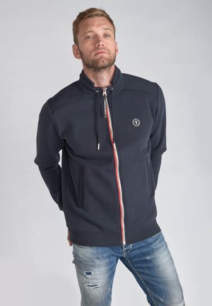 Marineblaue Zip-Up-Fleecejacke aus weichem Material mit hohem Kragen und rotem Akzent am Reißverschluss. Enthält Seitentaschen und Logodetails.