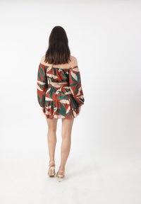 Schulterfreies Kleid in Rostfarbe mit grünen und cremefarbenen Blättern. Verfügt über einen smockierten Bund und einen ausgestellten Rock. Strukturierter Stoff.
