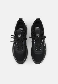 Mustat urheilukengät, joissa on hengittävä verkko-osa, kumipohja, nauhoitusdesign ja brändätyt vetoketjut. Raskaat yksityiskohdat sivuilla ja kielekkeessä.