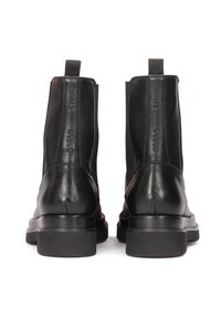 Botines de cuero negro con una textura suave, paneles laterales elásticos, lengüetas y una suela de goma gruesa para mayor estabilidad.