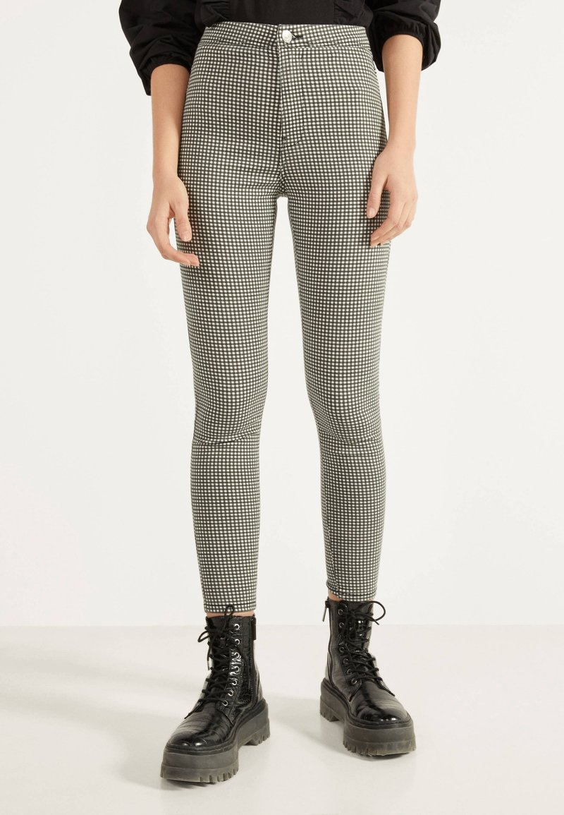 High-waisted black and white checkered leggings, form-fitting, made of stretchy material, paired with chunky black combat boots.
