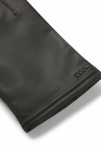 Zwarte lederen handschoen met een gladde textuur, voorzien van een gestikte rand en een geperst "BOSS"-logo op het polsgebied.
