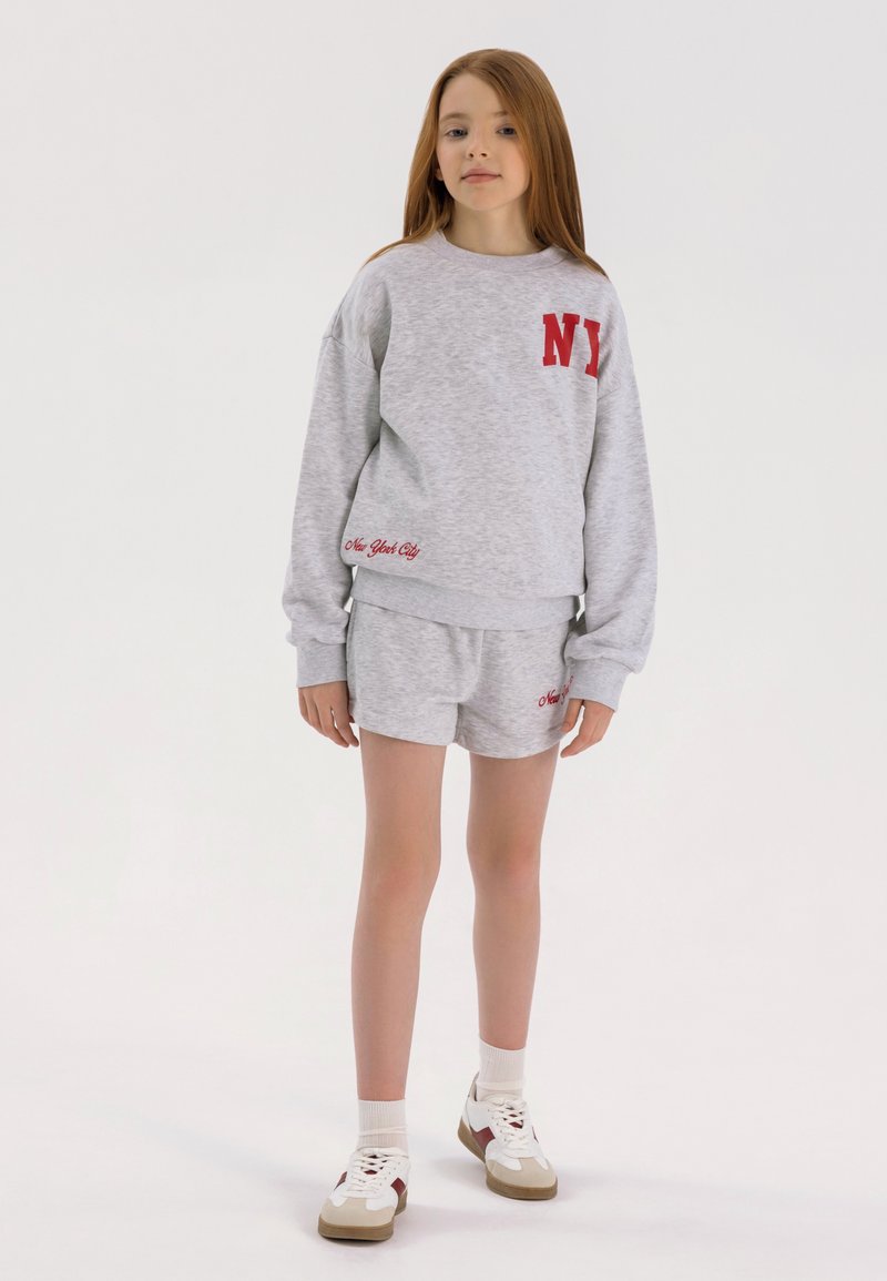 Grijze sweatshirt en short set, met rode borduursels van "NY" en "New York City", gemaakt van zachte stof, met een ontspannen pasvorm en geribde manchetten.