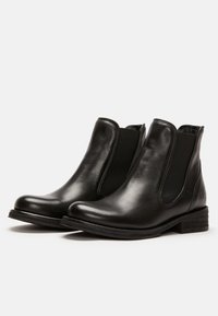 Botas de tobillo de cuero negro con paneles laterales elásticos, punta redondeada y suela de goma texturizada. Presenta un tacón bajo apilado para mayor estabilidad.