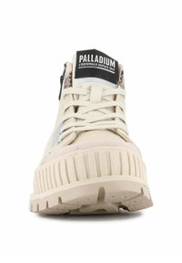 Sneaker high-top beige Palladium con suola spessa a righe, chiusura con lacci, cerniera laterale e patch logo nero sulla linguetta.