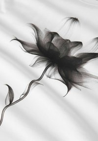 Zwart bloemenpatroon op witte stof, met delicate bloemblaadjes en een vloeiende steel, voorzien van een doorzichtige textuur en een glad oppervlak.