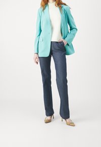 Tyrkysový blejzr, krémový pletený top, tmavé džíny a béžové lodičky s vysokým podpatkem a zlatými ozdobami. Jednoduché a čisté linie.