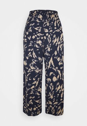 Marineblauwe broek met wijde pijpen, voorzien van een beige abstract bloemenpatroon en een elastische tailleband, afgebeeld tegen een witte achtergrond.