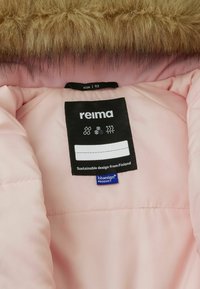 Interno di una giacca isolata rosa, con un'etichetta nera recante il nome del marchio "reima" e simboli di cura, accompagnata da un'etichetta blu "bluesign".