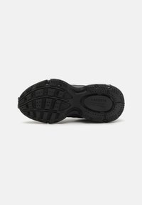 Melna sneaker zole ar teksturētu gumiju, kas satur dziļas rievas un rakstainu virsmu saķerei. Lacoste logo iepresēts.