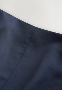 Tissu bleu marine foncé avec une couture verticale au centre sur un fond clair, montrant une texture lisse et un détail de couture.