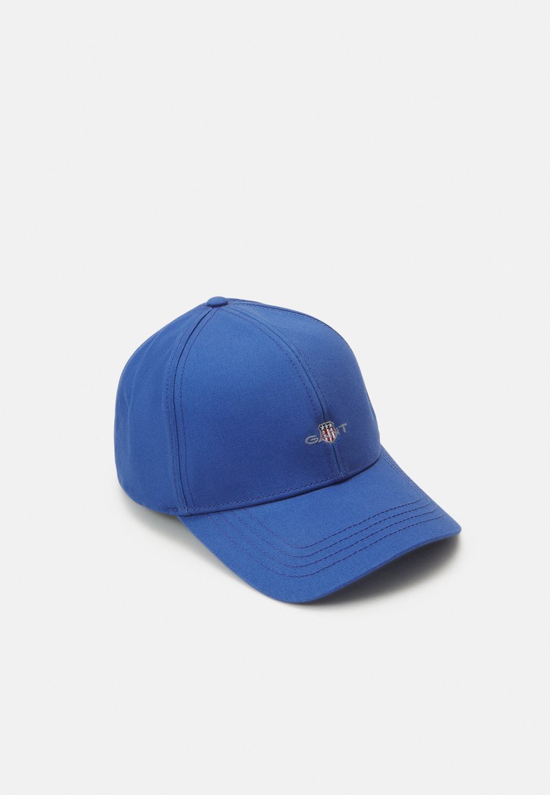Cappellino da baseball blu in tessuto, con visiera cucita, design a sei pannelli e un logo sulla parte anteriore. Texture liscia, stile casual.