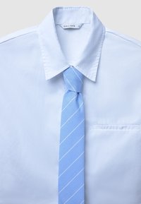 Weißes Hemd mit Kragen und einer Brusttasche, kombiniert mit einer hellblauen Krawatte mit weißen diagonalen Streifen. Das Etikett trägt die Aufschrift "CALLIOPE."