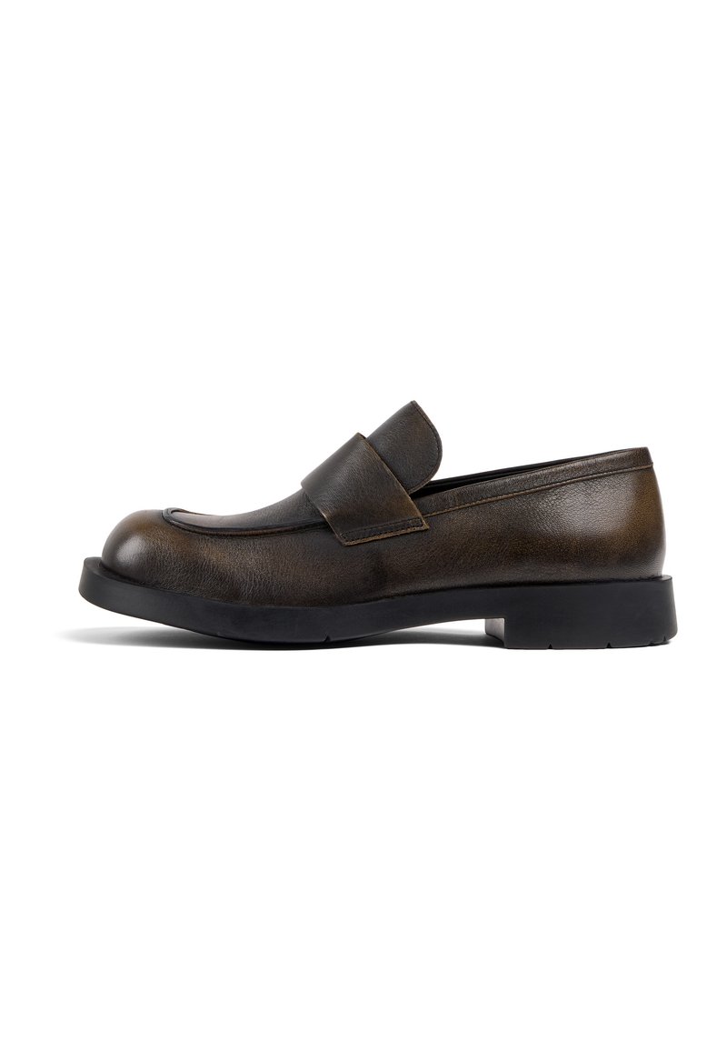 Brown leather loafer with a rounded toe, a flat black rubber sole, and a wide strap across the upper for secure fitting.