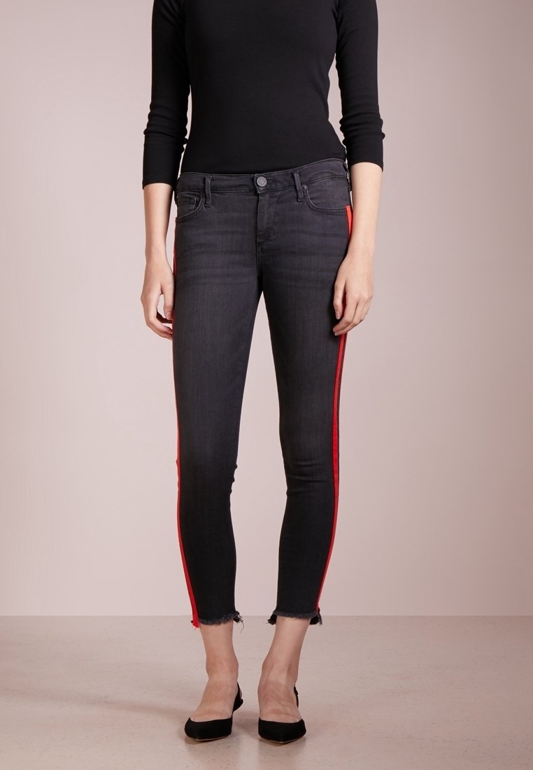 Svarta skinny jeans med röda sidosträck, med midjehöjd, lätt fransning vid fållen och klassisk femfickdesign.
