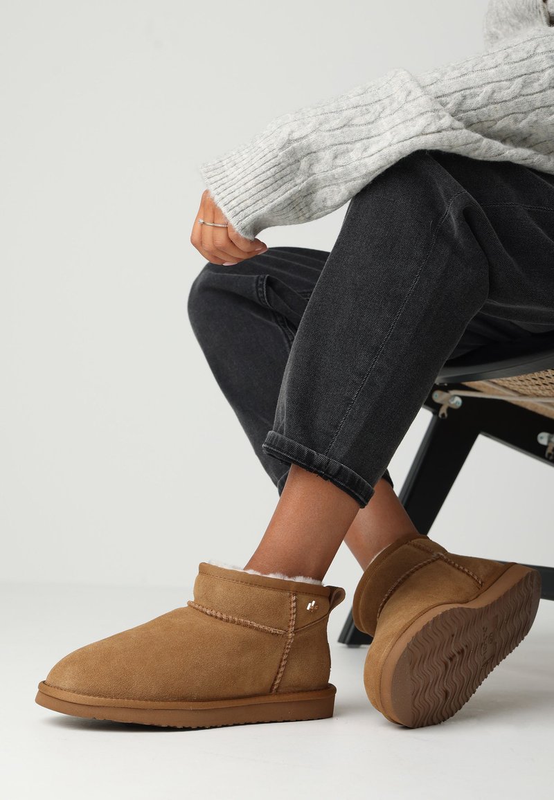 Hnědé semišové kotníkové boty s měkkou fleecovou podšívkou, s texturovanou gumovou podrážkou a ozdobným prošíváním podél švů.