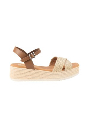 Sandalia de cuña con tiras delanteras trenzadas en beige, correa marrón en el tobillo con hebilla plateada y suela de plataforma texturizada en beige claro.