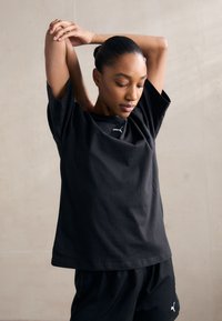 Black cotton T-shirt with a relaxed fit, crew neck, and short sleeves. Features a subtle white logo on the chest.