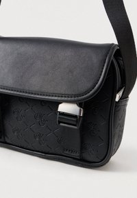 Borsa a tracolla nera realizzata in pelle sintetica testurizzata. Presenta una chiusura con pattina, ferramenta in argento e un motivo a logo in rilievo sulla superficie.