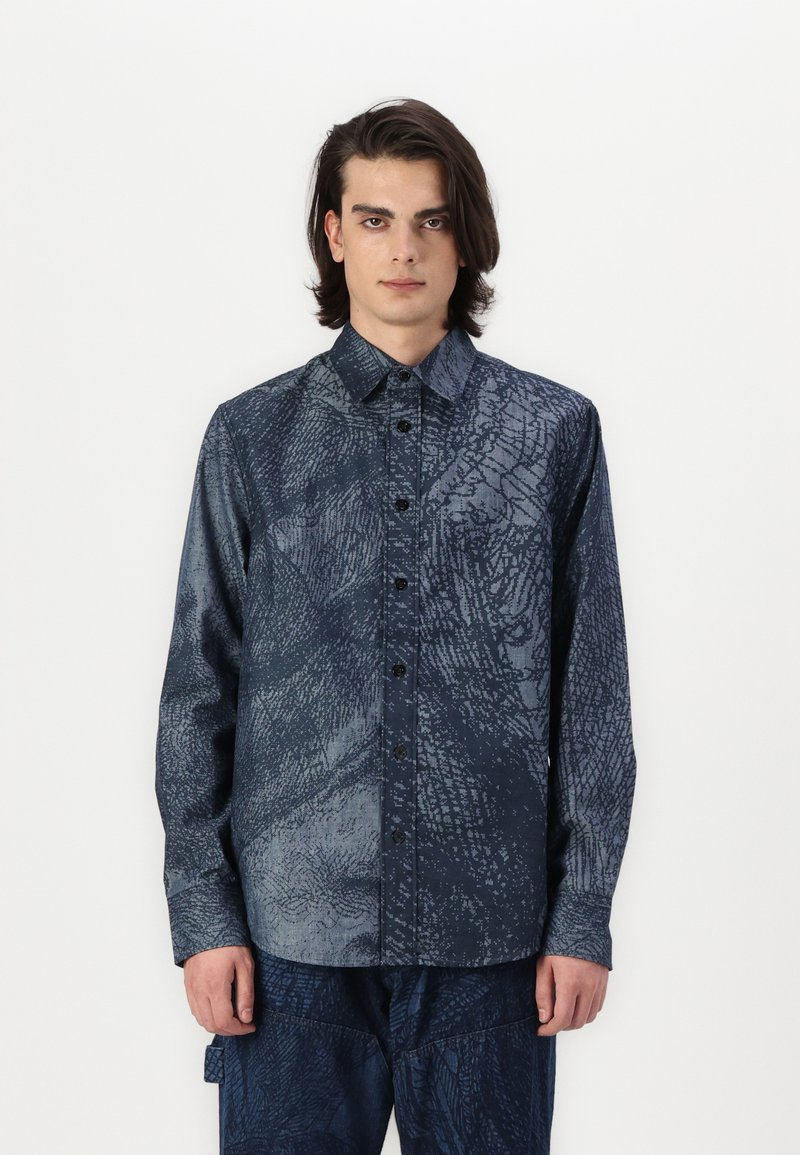 Camicia a maniche lunghe in tessuto blu scuro con una trama testurizzata. Caratterizzata da una apertura con bottoni e un colletto classico. Adatta per un abbigliamento casual.