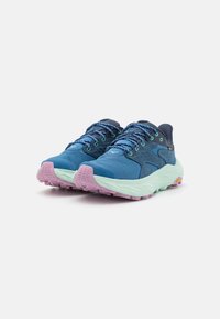 Siniset urheilukengät verkkomateriaalista valmistetulla päällisellä, teksturoiduilla tummansinisen sävyisillä yksityiskohdilla, vihreillä nauhoilla ja vaaleanpunaisella pohjallisella. Varustettu pehmusteella ja karkealla pohjalla.