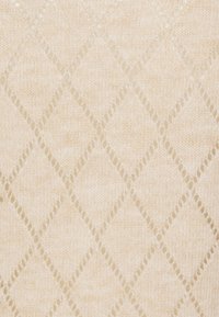 Dzianina w jasnobeżowym kolorze z wzorem diamentu. Tekstura jest miękka, z otwartymi oczkami tworzącymi delikatny wygląd.