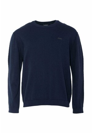 Tumši zils džemperis ar apaļu kakla izgriezumu, garām piedurknēm, mīkstu tekstūru un brīvu piegriezumu, uz krūtīm maza un neuzkrītoša logotipa plāksnīte.